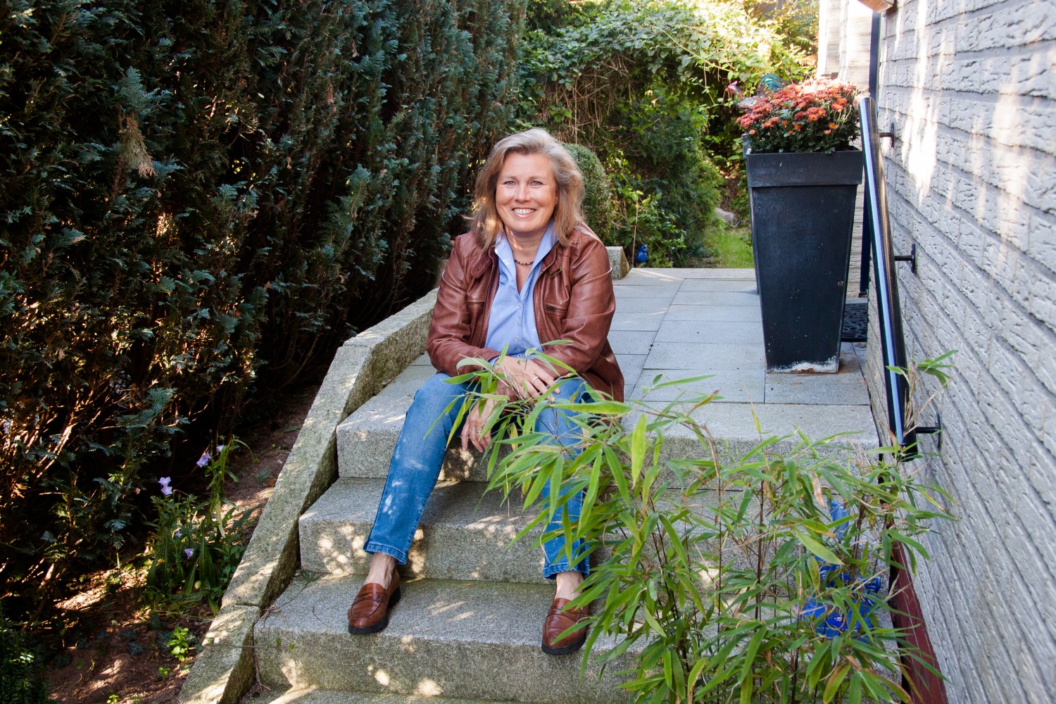 Feng Shui Imperial Consultant Bischoff sitzt lächelnd auf der Treppe vor dem Haus zwischen Hamburg und Lübeck